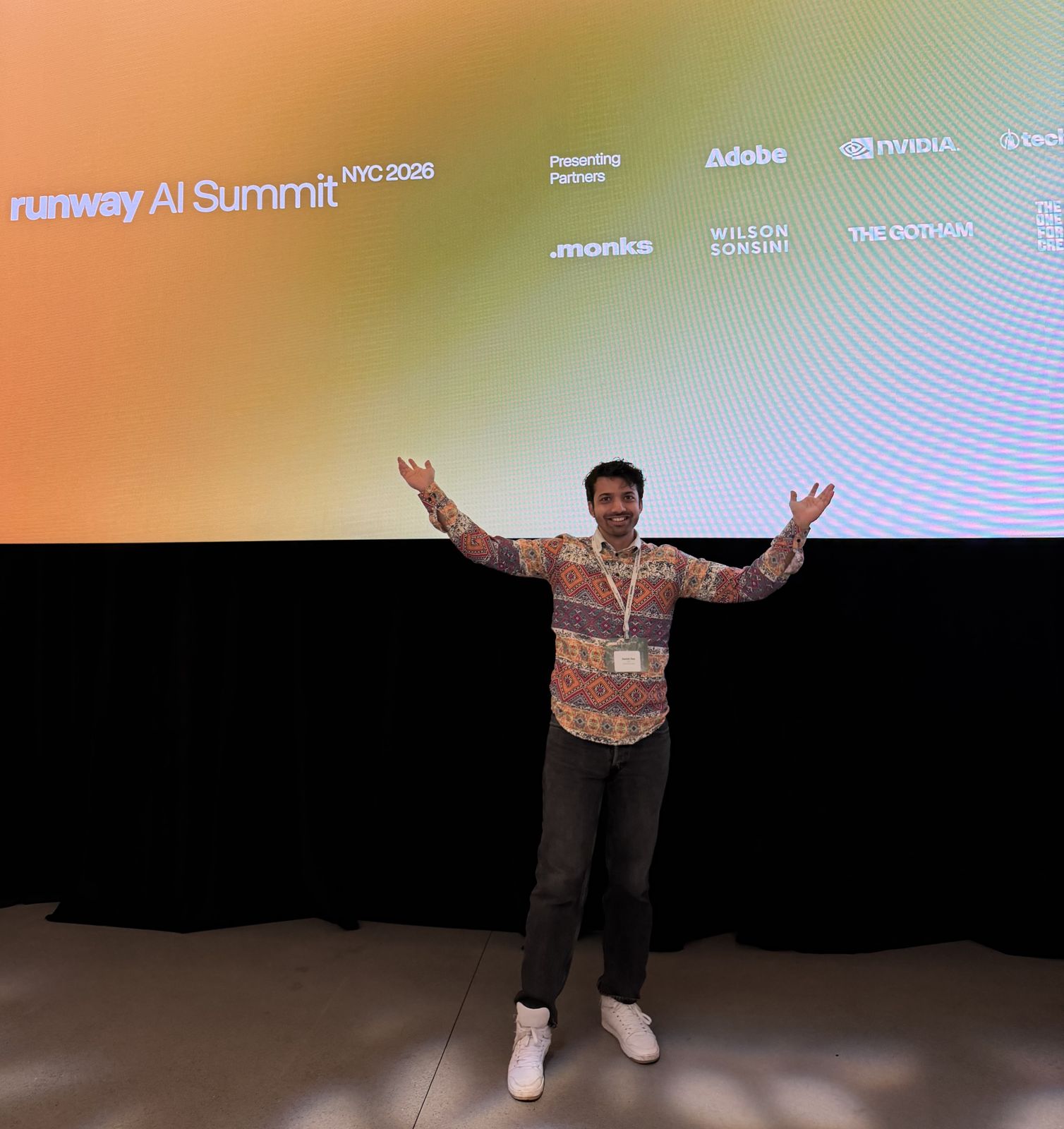 Ashish Dsa with arms raised on stage below the Runway AI Summit NYC 2026 screen